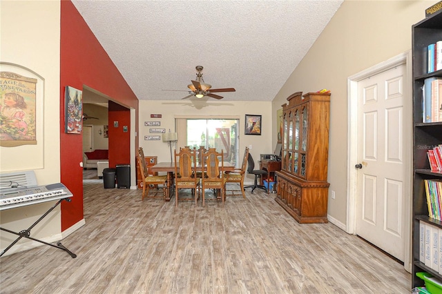 dining area with ceiling fan, light wood-type flooring, a textured ceiling, and vaulted ceiling