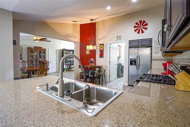 kitchen with pendant lighting, sink, a textured ceiling, appliances with stainless steel finishes, and washer / clothes dryer