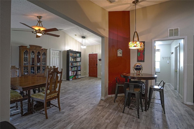 dining area with hardwood / wood-style floors, a textured ceiling, ceiling fan, and lofted ceiling