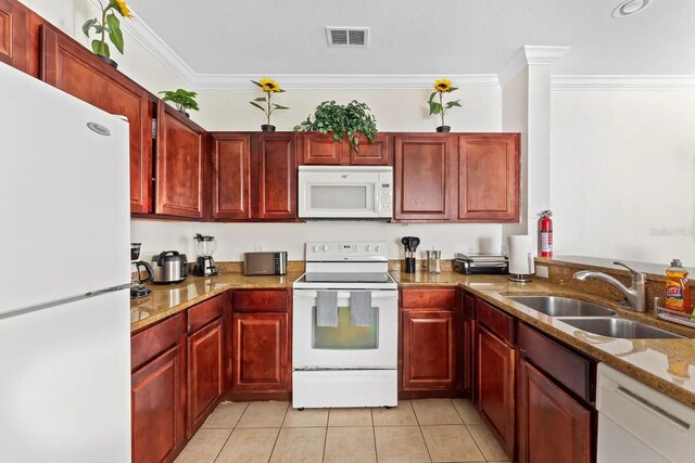 kitchen featuring sink, light stone counters, crown molding, light tile patterned floors, and white appliances