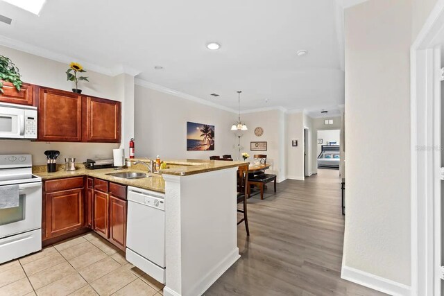 kitchen featuring sink, ornamental molding, light wood-type flooring, white appliances, and kitchen peninsula