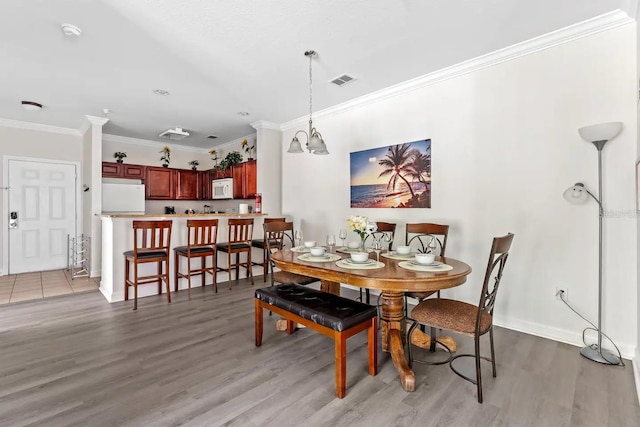 dining space featuring crown molding and light hardwood / wood-style flooring