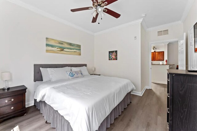 bedroom featuring ceiling fan, wood-type flooring, and ornamental molding