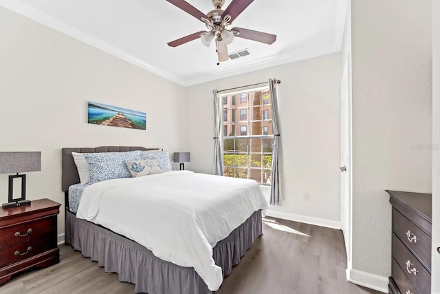 bedroom with ceiling fan, ornamental molding, and light wood-type flooring