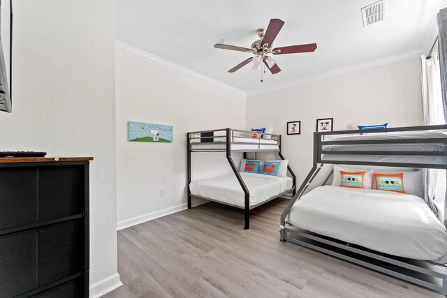 bedroom featuring ceiling fan, light wood-type flooring, and ornamental molding