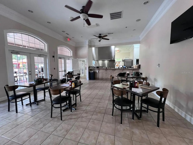 dining area with ceiling fan, a high ceiling, french doors, light tile patterned floors, and crown molding