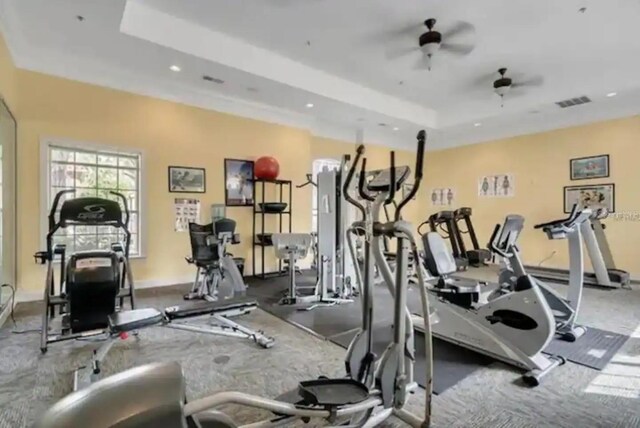 gym featuring ceiling fan and a tray ceiling