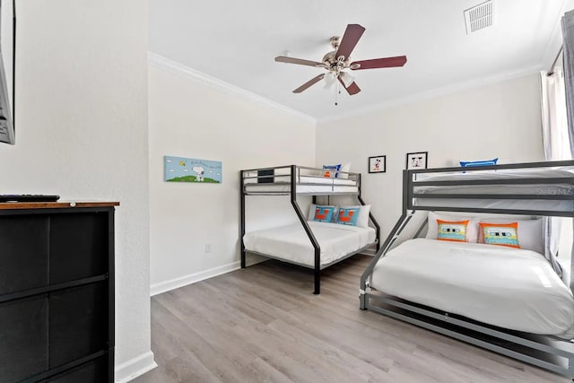 bedroom with visible vents, baseboards, a ceiling fan, wood finished floors, and ornamental molding