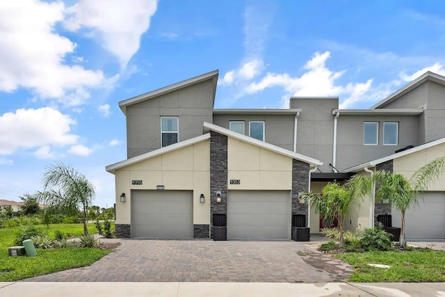 view of front of home featuring stone siding, driveway, and stucco siding