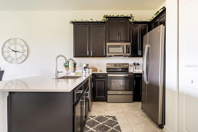 kitchen with backsplash, sink, kitchen peninsula, light tile patterned flooring, and stainless steel appliances