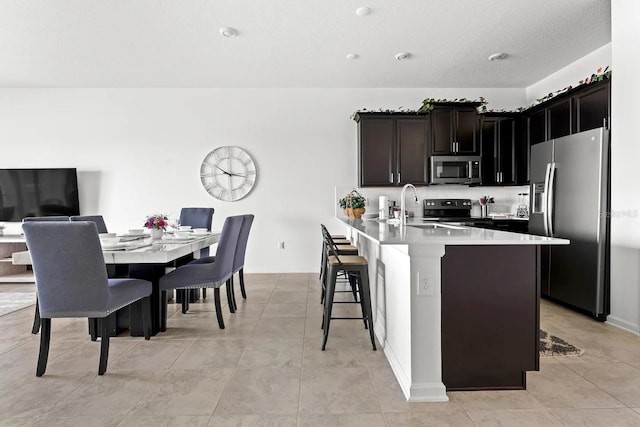 kitchen featuring appliances with stainless steel finishes, light tile patterned floors, a kitchen bar, and sink