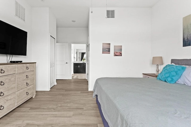 bedroom with connected bathroom and light hardwood / wood-style flooring