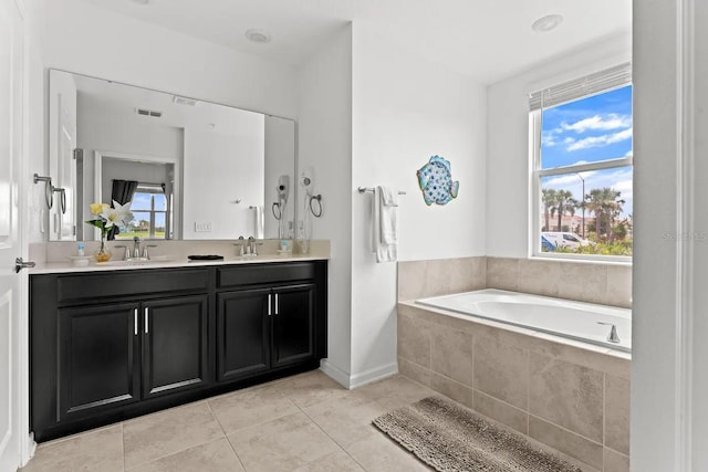 bathroom featuring a wealth of natural light, a relaxing tiled tub, tile patterned flooring, and dual bowl vanity