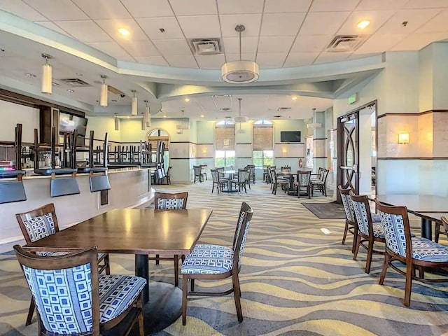 carpeted dining space featuring a paneled ceiling