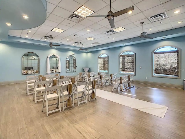 interior space with a paneled ceiling, ceiling fan, and light hardwood / wood-style flooring