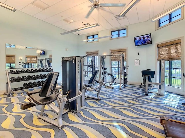 workout area with a towering ceiling, carpet flooring, and ceiling fan