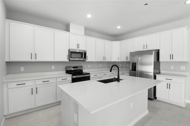 kitchen with stainless steel appliances, a kitchen island with sink, sink, and white cabinets