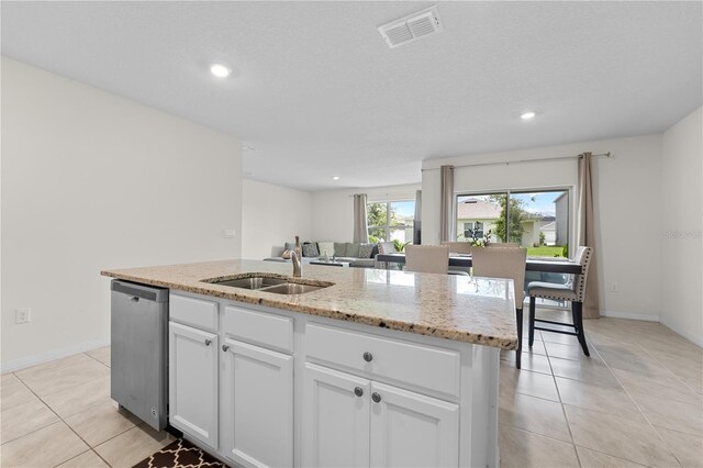 kitchen featuring stainless steel dishwasher, a kitchen island with sink, white cabinets, light tile patterned floors, and sink