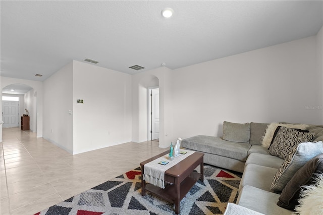 living room with visible vents, arched walkways, baseboards, and light tile patterned flooring