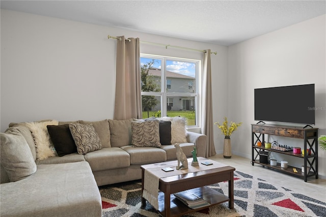 living room featuring light tile patterned floors, a textured ceiling, and baseboards