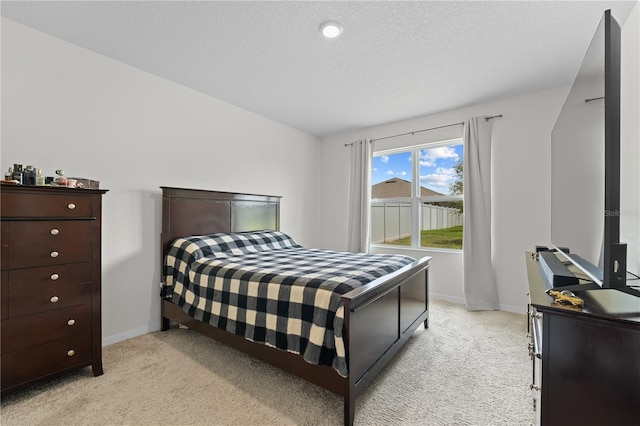 bedroom featuring light carpet, baseboards, and a textured ceiling