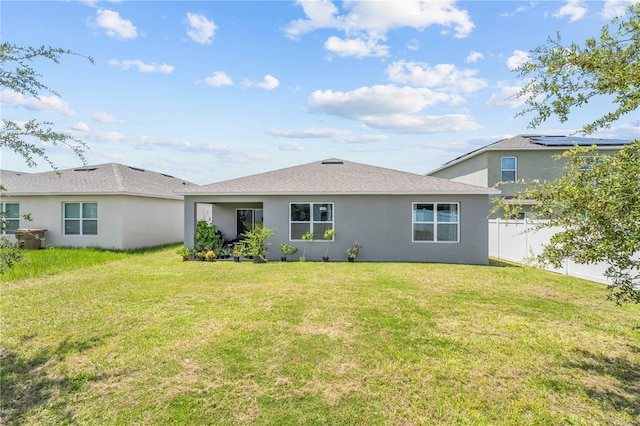 back of house featuring a yard, fence, and stucco siding