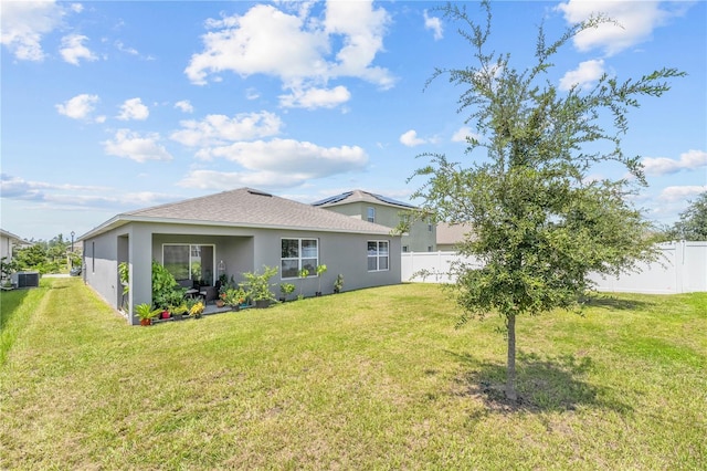 rear view of property featuring stucco siding, a yard, a fenced backyard, and central air condition unit