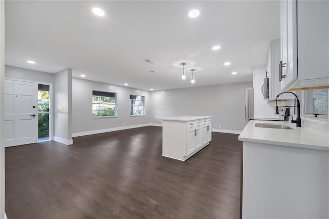 kitchen with appliances with stainless steel finishes, white cabinetry, sink, a center island, and dark wood-type flooring