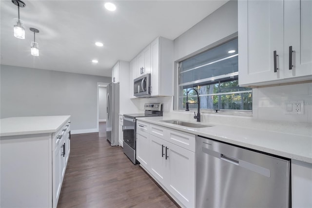 kitchen featuring sink, dark hardwood / wood-style floors, stainless steel appliances, pendant lighting, and white cabinets