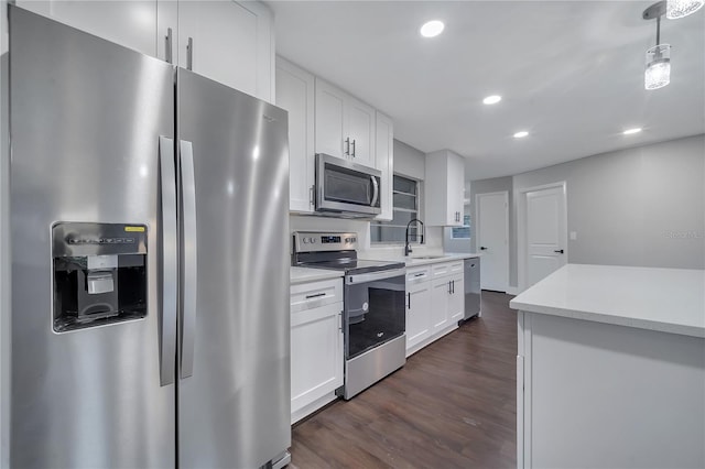 kitchen with appliances with stainless steel finishes, pendant lighting, white cabinets, and dark hardwood / wood-style flooring