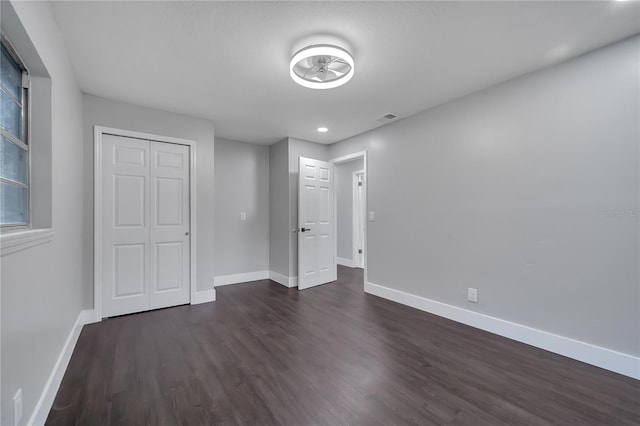 unfurnished bedroom featuring a closet and dark wood-type flooring