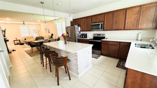 kitchen with light tile patterned floors, stainless steel appliances, light countertops, a sink, and a kitchen bar