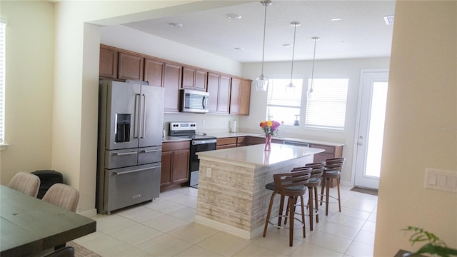 kitchen featuring a center island, pendant lighting, a breakfast bar area, stainless steel appliances, and light countertops