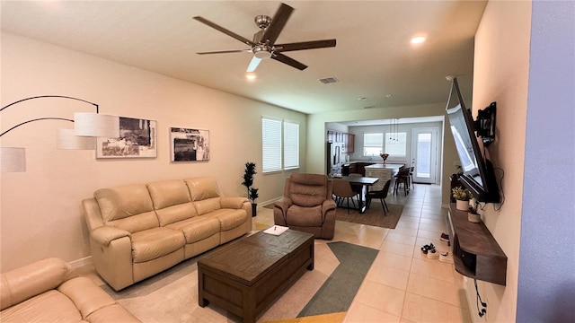 living room with a ceiling fan, visible vents, baseboards, and light tile patterned floors