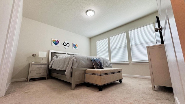 bedroom featuring light carpet, a textured ceiling, and baseboards