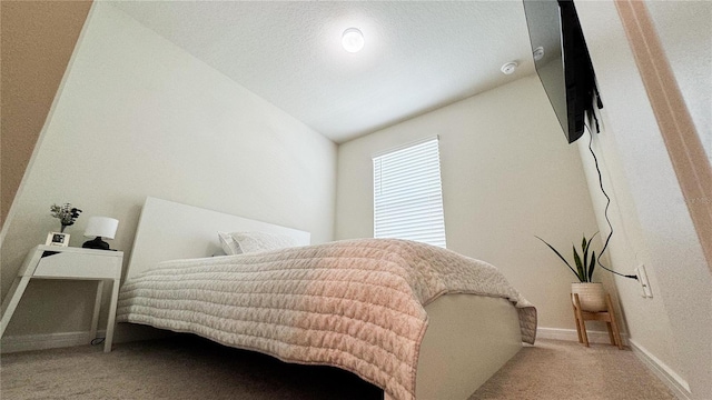 carpeted bedroom featuring lofted ceiling, baseboards, and a textured ceiling