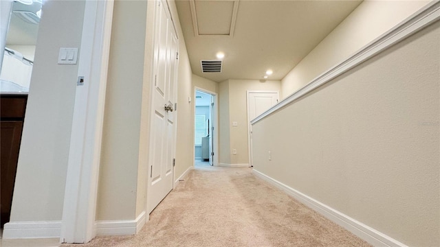 corridor with baseboards, visible vents, and light colored carpet