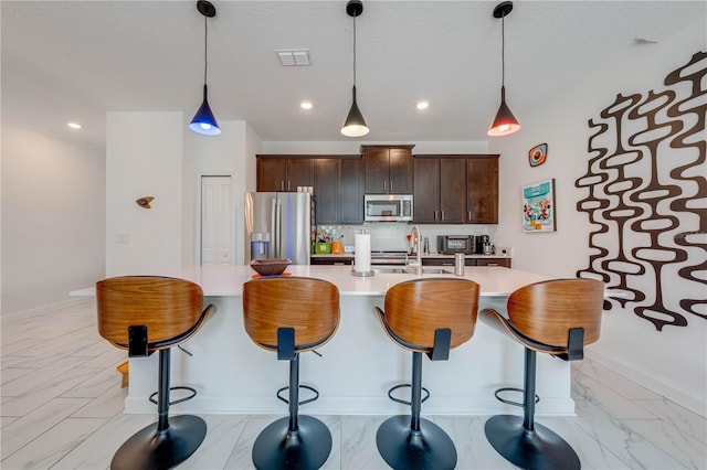 kitchen with marble finish floor, stainless steel appliances, hanging light fixtures, and light countertops