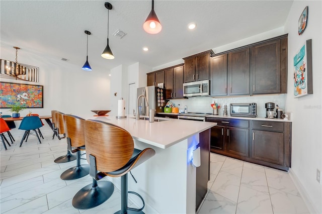 kitchen with marble finish floor, stainless steel appliances, light countertops, pendant lighting, and a sink