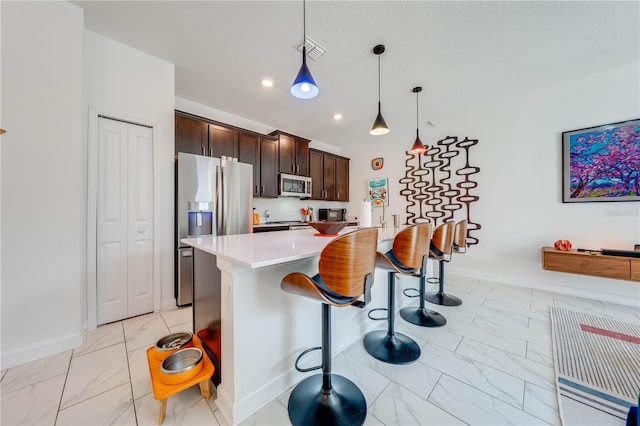 kitchen featuring stainless steel appliances, visible vents, marble finish floor, hanging light fixtures, and light countertops