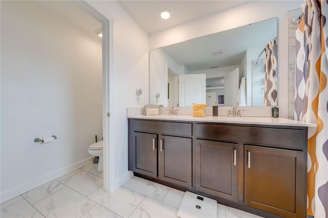 bathroom with marble finish floor, double vanity, toilet, a sink, and baseboards