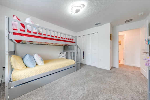 bedroom featuring carpet, a textured ceiling, visible vents, and a closet