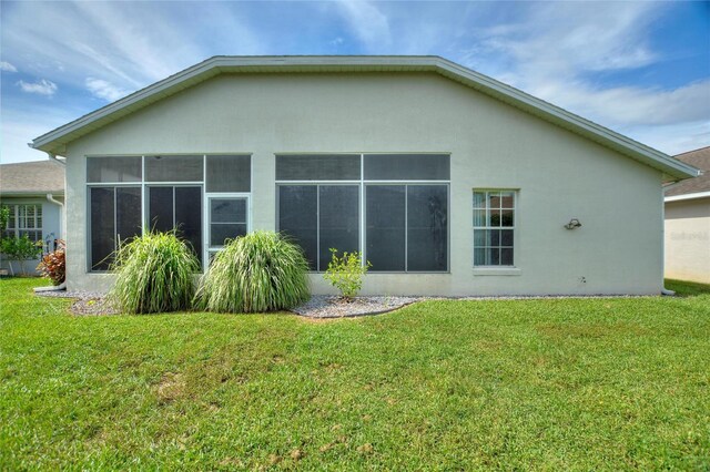 rear view of property featuring a yard and a sunroom