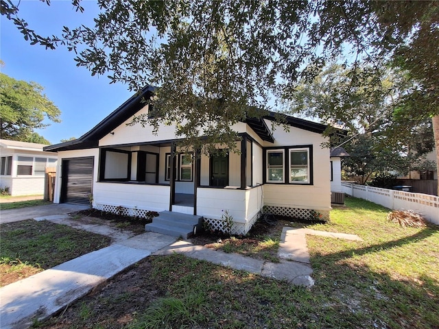 view of front of home with a front lawn, central AC unit, and a garage