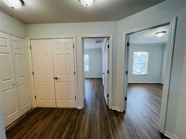 corridor featuring a textured ceiling, dark hardwood / wood-style floors, and ornamental molding