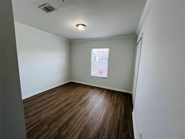 empty room with hardwood / wood-style flooring and crown molding