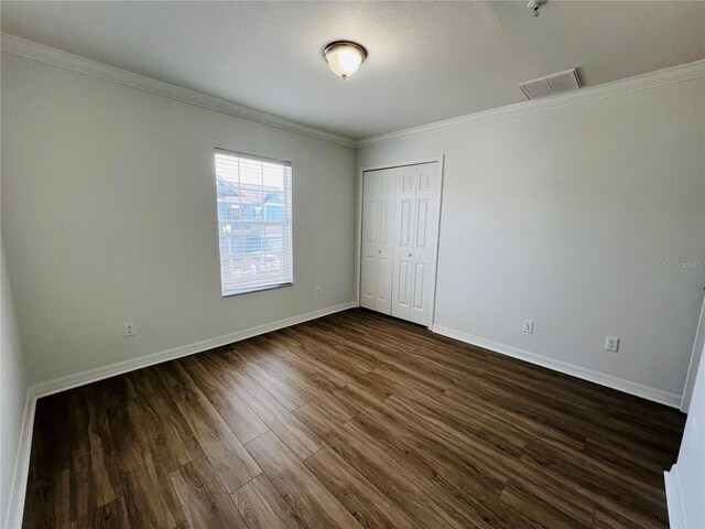 unfurnished bedroom featuring a closet, crown molding, and hardwood / wood-style floors