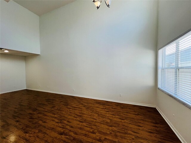 empty room with hardwood / wood-style floors and a towering ceiling