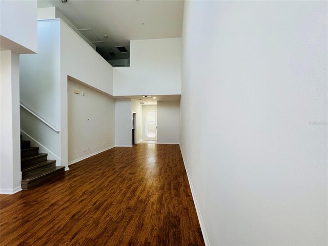 spare room with a towering ceiling and wood-type flooring