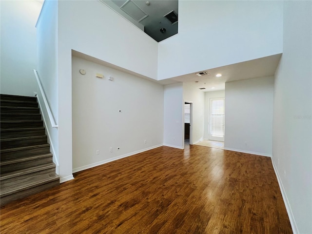 unfurnished living room with a towering ceiling and hardwood / wood-style floors